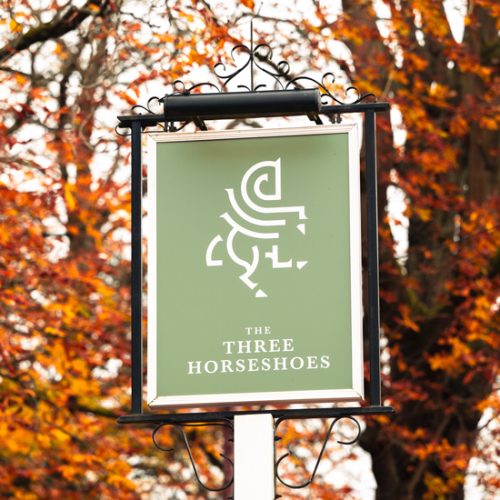 The Three Horseshoes in Watford, green sign with white horse logo.
